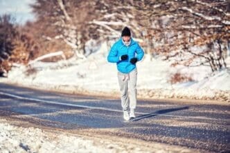 An athletic man jogs and trains outdoors in a park with snow on a cold day.