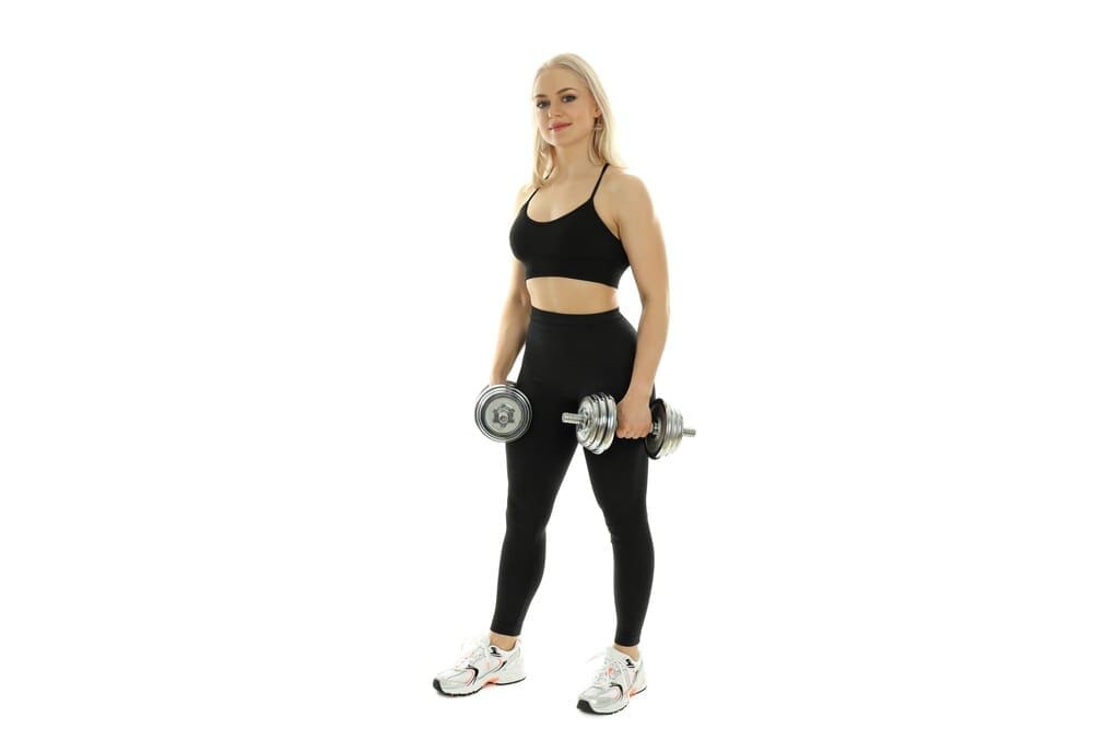 A fit, athletic woman poses on a white background.