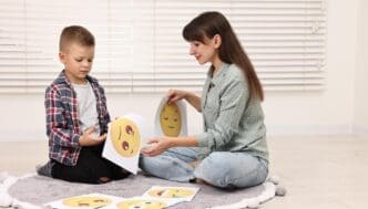 A young boy with autism selects an emoticon with a psychologist in a mental health center.