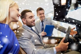 A happy couple and a car dealer stand together in a car showroom with a snowy effect overlay.