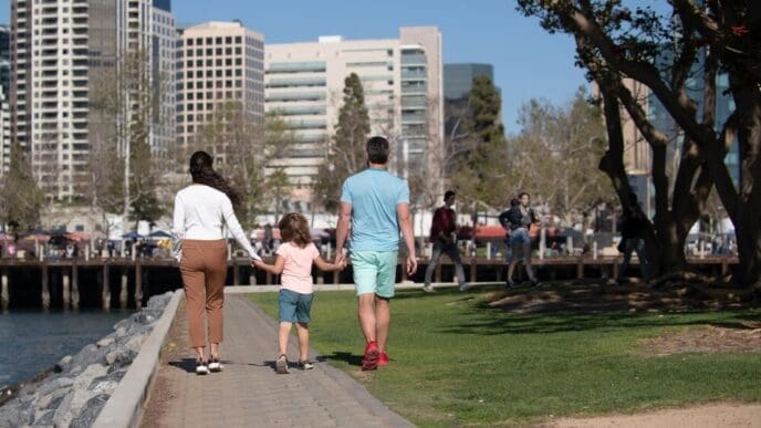 Back view of a smiling family walks down a city street, enjoying a casual day out.