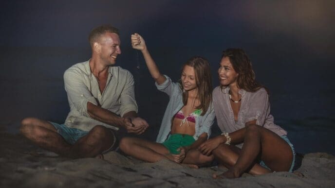 A smiling family enjoys an evening on a sandy beach, playing together.