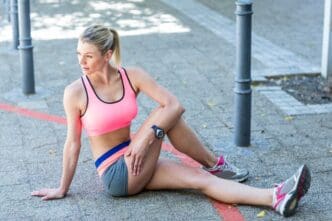 A woman with long hair is stretching her leg out on the floor.