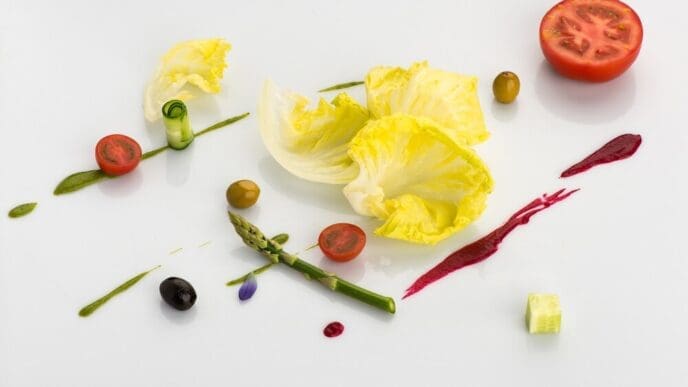 Sliced tomatoes and asparagus are artistically arranged on a white surface.
