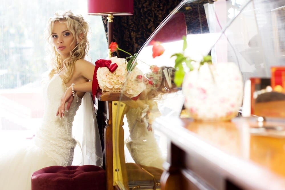 A young bride in a white wedding dress smiles.