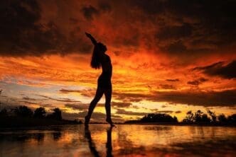 Silhouette of a woman with long hair poses on a beach.