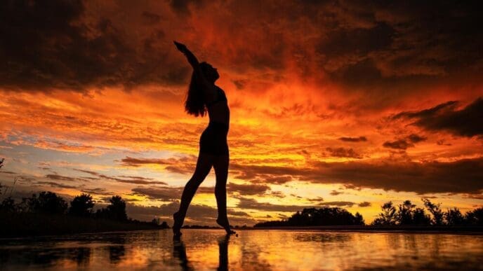 Silhouette of a woman with long hair poses on a beach.