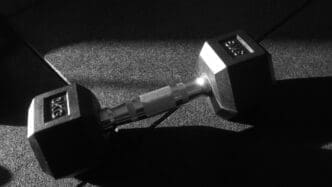 Black and white photo shows a 3 kg dumbbell resting on the floor.
