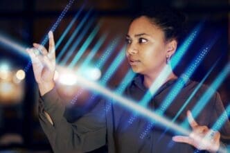 Black woman's hands interact with a glowing, futuristic digital interface in a dimly lit office setting.