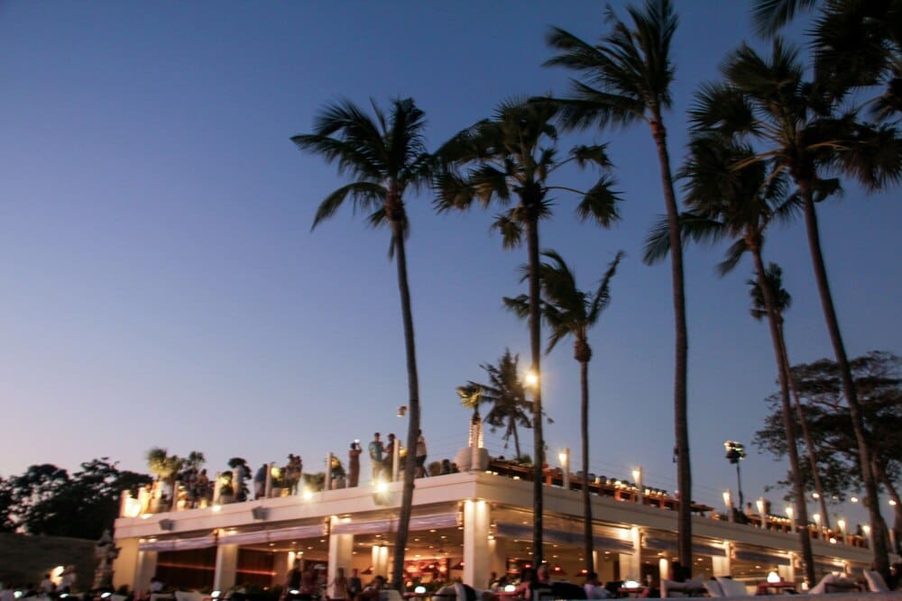Blurred image of a beach party shows many people enjoying themselves, conveying a festive atmosphere.