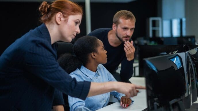 Two business colleagues, a man and a woman, collaborate in cybersecurity at a desk in a modern office setting.