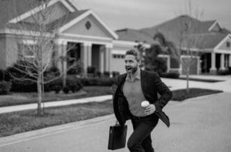 A businessman in a suit runs down a street in a residential neighborhood.