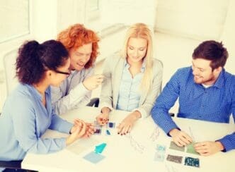 A diverse group of smiling people in a modern office setting collaboratively examines a sketch.