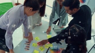 Business people sit around a conference table, participating in a meeting with a projected graphic.