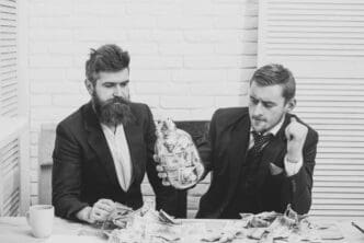Business partners looking thoughtful at a meeting with a jar of cash in an office.