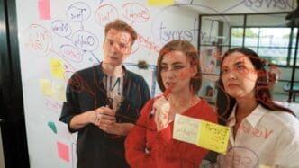 Business team members brainstorming ideas, using colorful sticky notes on a clean, white surface.