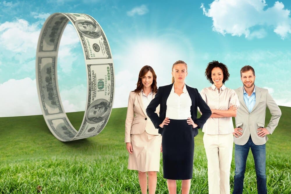 A business team smiles at the camera while standing in a field with a blue sky in the background.