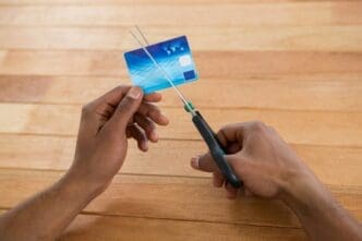A person uses scissors to cut a credit card in half.