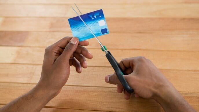 A person uses scissors to cut a credit card in half.