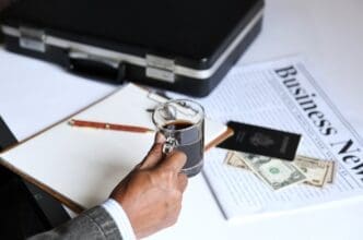 A businessman holds a cup of coffee and a newspaper.