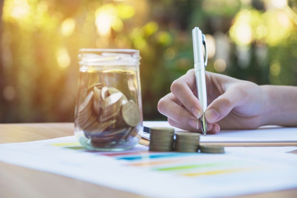 A businesswoman analyzes financial data while stacks of coins sit on the table.