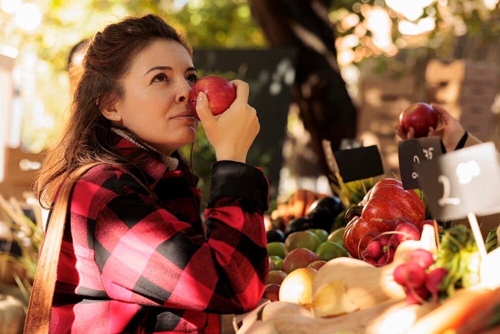 A Caucasian woman browses fresh produce at a local farmers market.