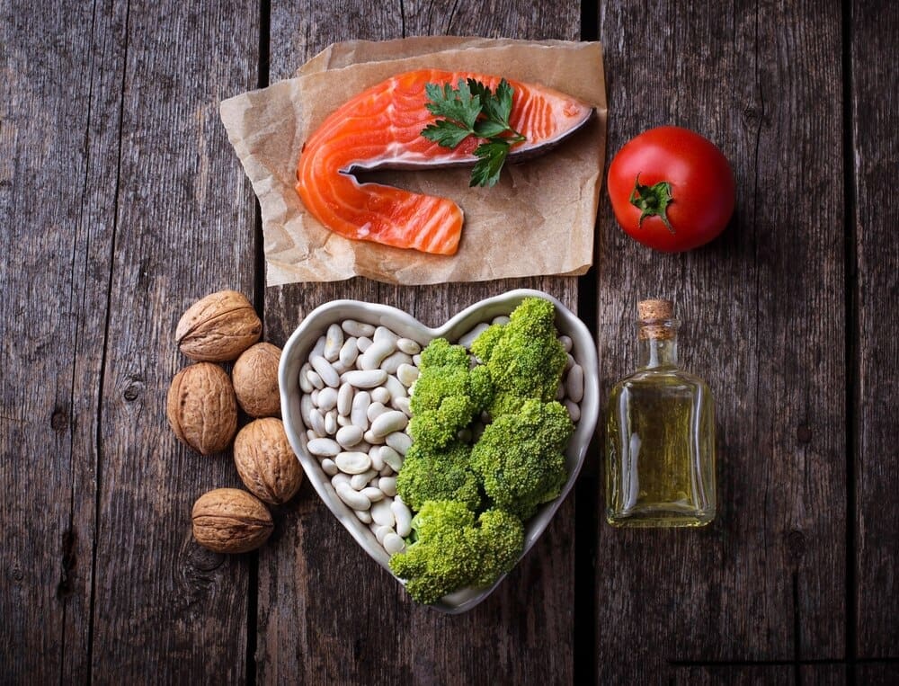 A close-up shot showcases a variety of heart-healthy foods, such as fruits and vegetables, arranged to emphasize a diet focused on lowering cholesterol.
