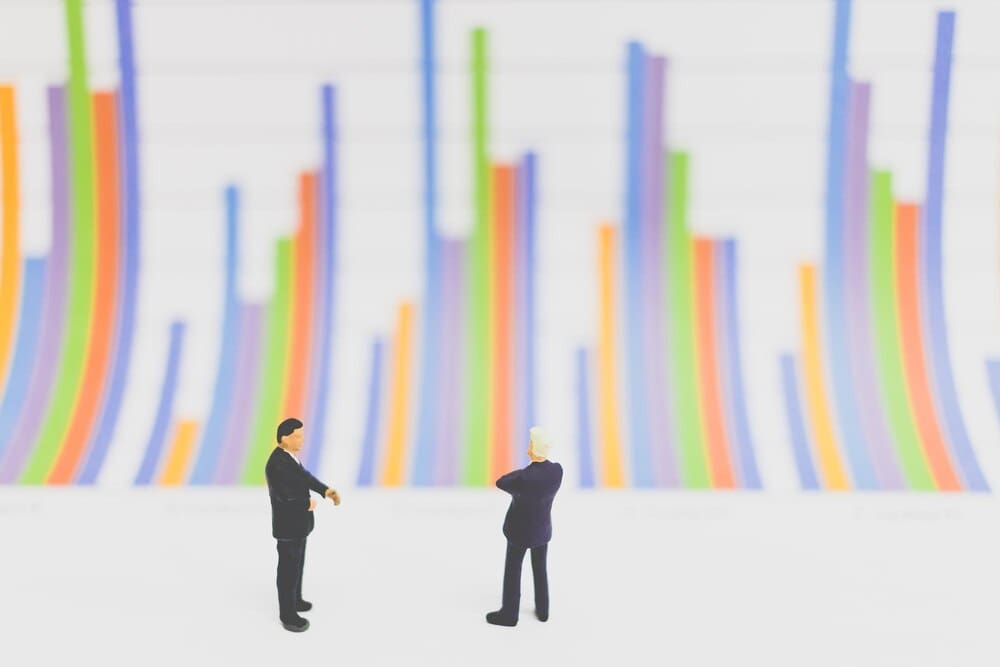 Close-up view shows small figurines arranged in front of a bar graph on a table.