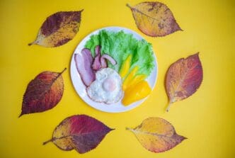 A close-up shows a breakfast plate garnished with leaves against a yellow background.