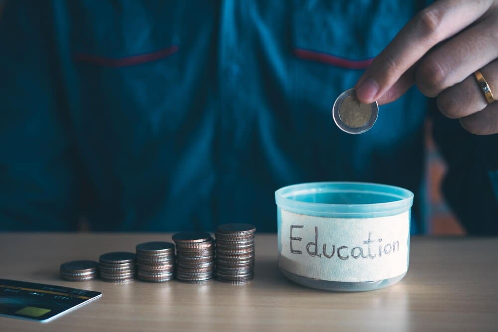 Close-up of a hand holding coins resting on a table.