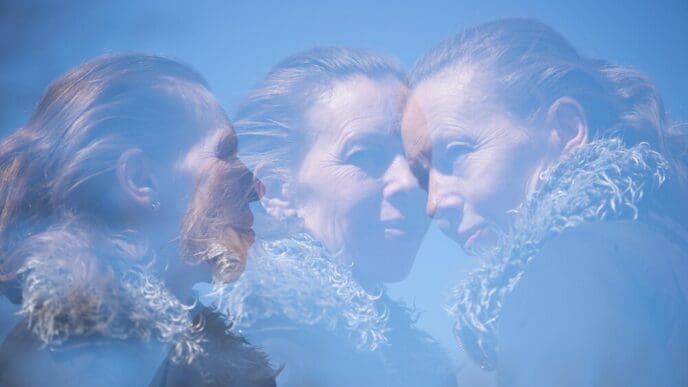 A young woman's face is seen in a close-up shot, set against a bright blue sky.
