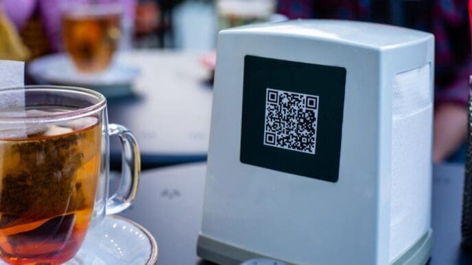 Close-up of a stainless steel napkin dispenser with a QR code for a digital menu.