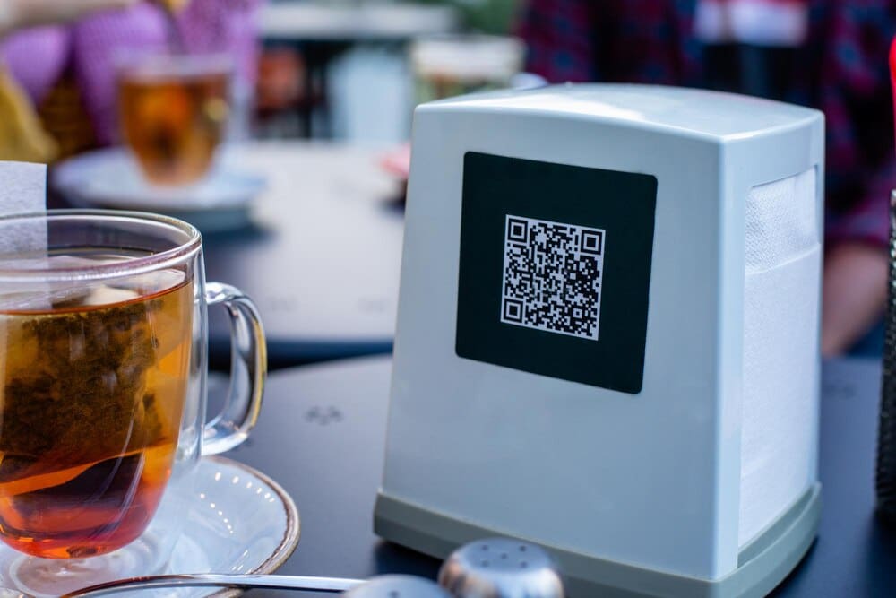 Close-up of a stainless steel napkin dispenser with a QR code for a digital menu.