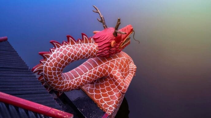 A close-up shot shows the front of a dragon boat on a lake, with decorative carvings and a colorful dragon head.