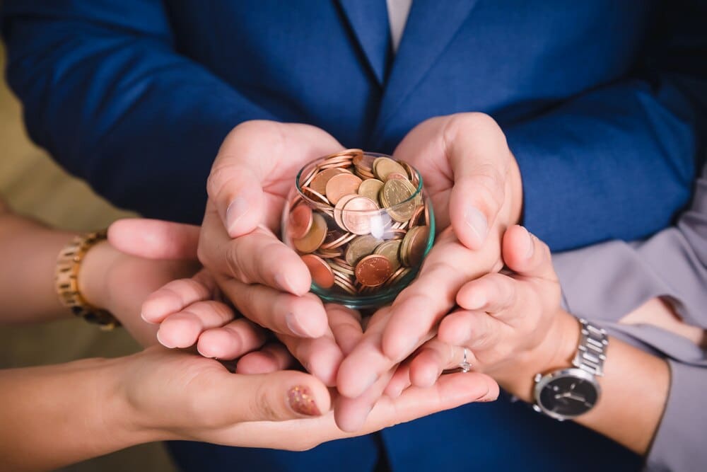 Close-up of hands holding a collection of coins, illustrating the concept of saving money.