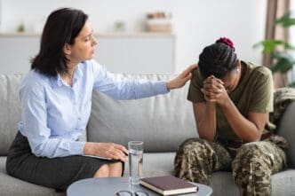A psychologist comforts an African American military woman during a therapy session.