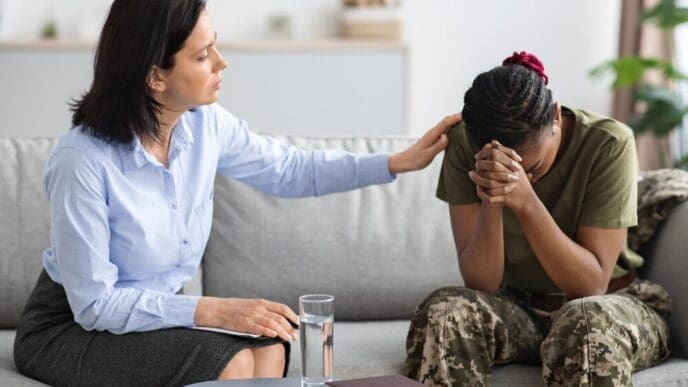 A psychologist comforts an African American military woman during a therapy session.