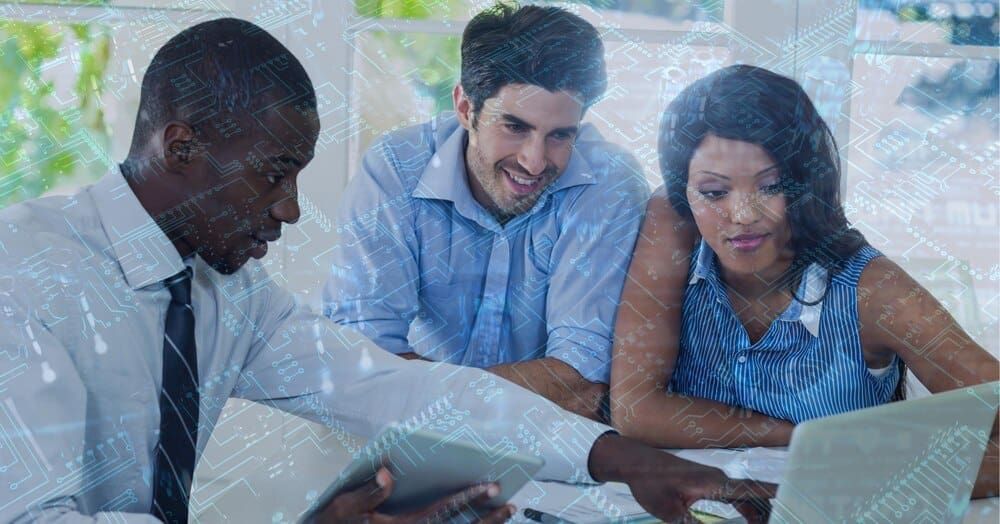 A close-up of a computer circuit board is overlaid on business people using a laptop.