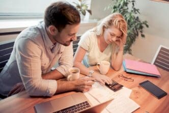 A couple reviews financial documents together while seated in their living room.