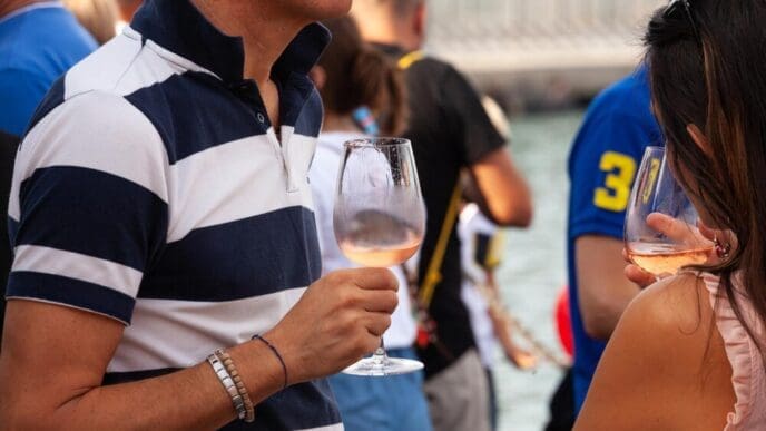 A man and a woman smile while holding glasses of Prosecco at an event.