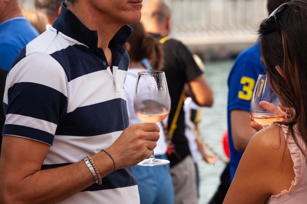 A man and a woman smile while holding glasses of Prosecco at an event.