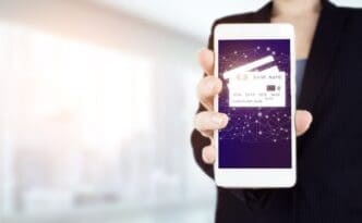 A hand holds a smartphone displaying a digital hologram of a credit card icon, representing a network connection on a virtual screen.
