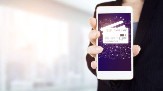 A hand holds a smartphone displaying a digital hologram of a credit card icon, representing a network connection on a virtual screen.