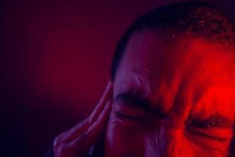 Cropped image shows a man with a frustrated expression against a solid-colored background.