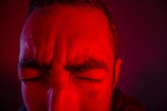 Cropped image shows a man with a frustrated expression against a solid background.