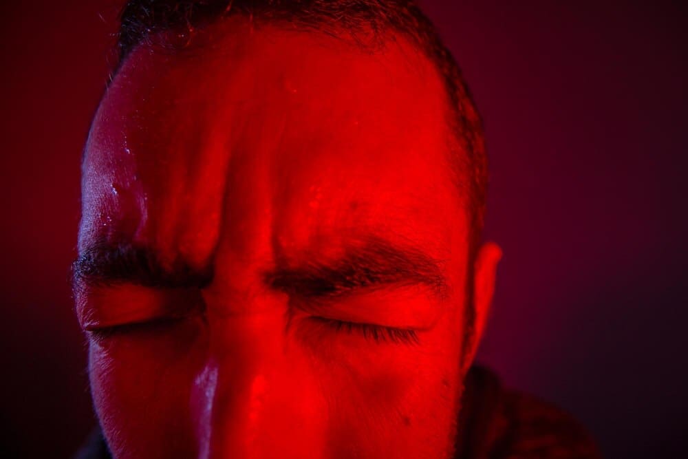 Cropped image shows a man with a frustrated expression against a solid background.