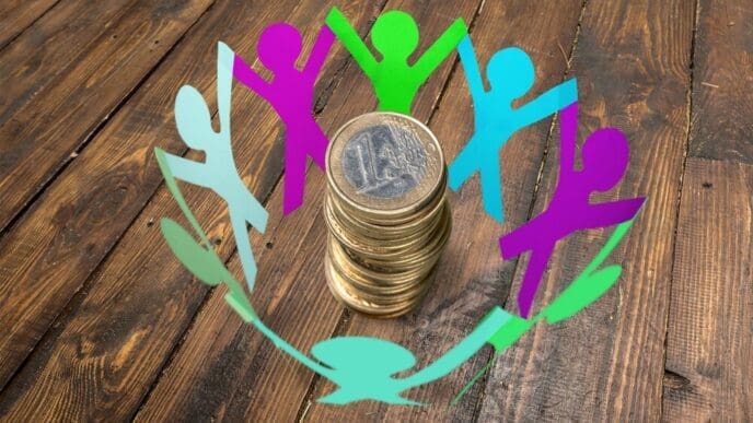 Paper cut-out figures gather around a stack of hundred-dollar bills, illustrating a crowdfunding concept.