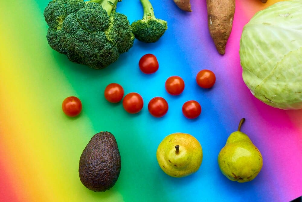Overhead shot of various fresh vegetables arranged on a colorful background.