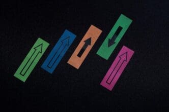 Overhead view of colorful arrow symbols pointing in opposing directions on a textured surface.