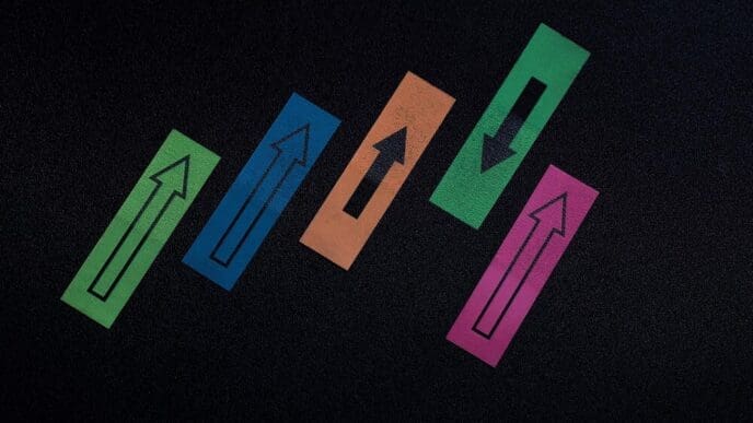 Overhead view of colorful arrow symbols pointing in opposing directions on a textured surface.